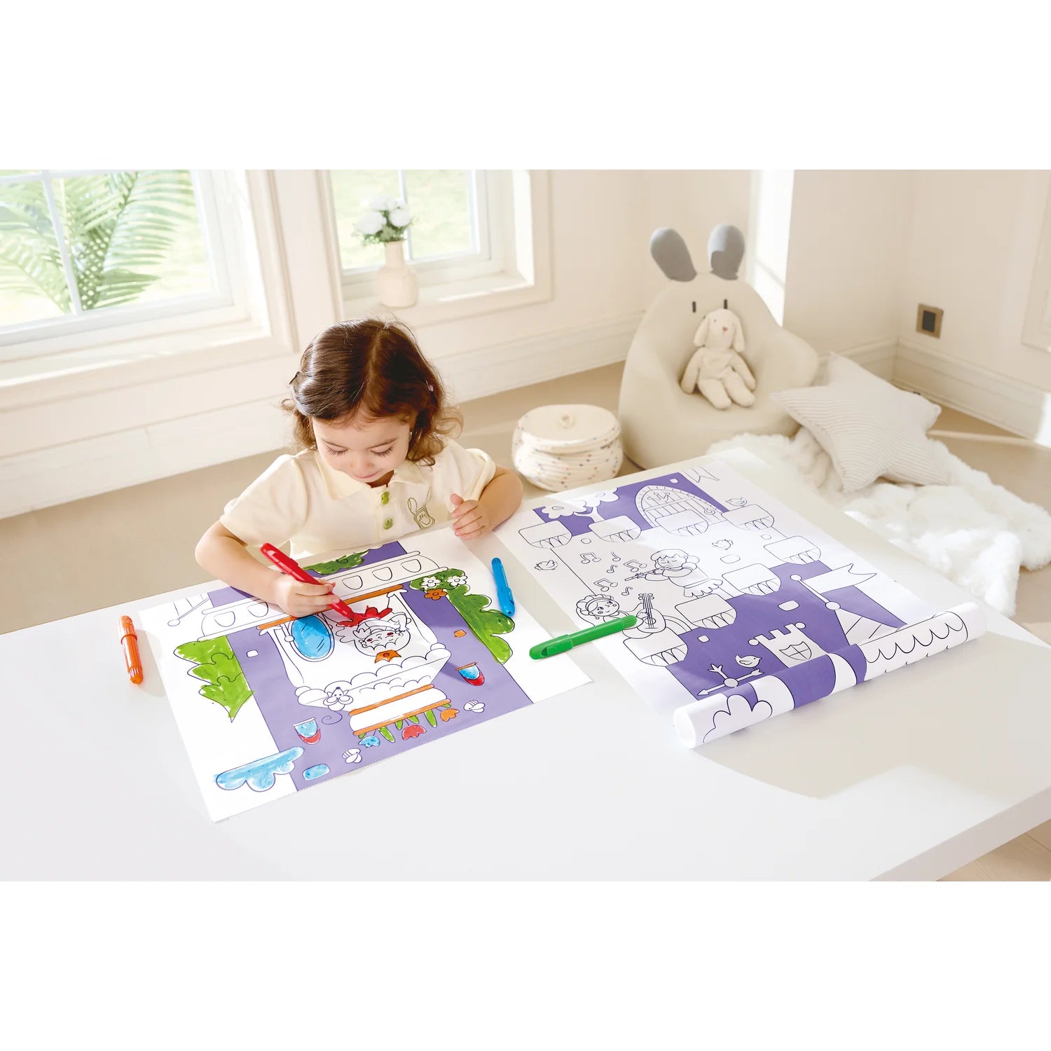 Child coloring on a table with coloring books and crayons in a bright room.