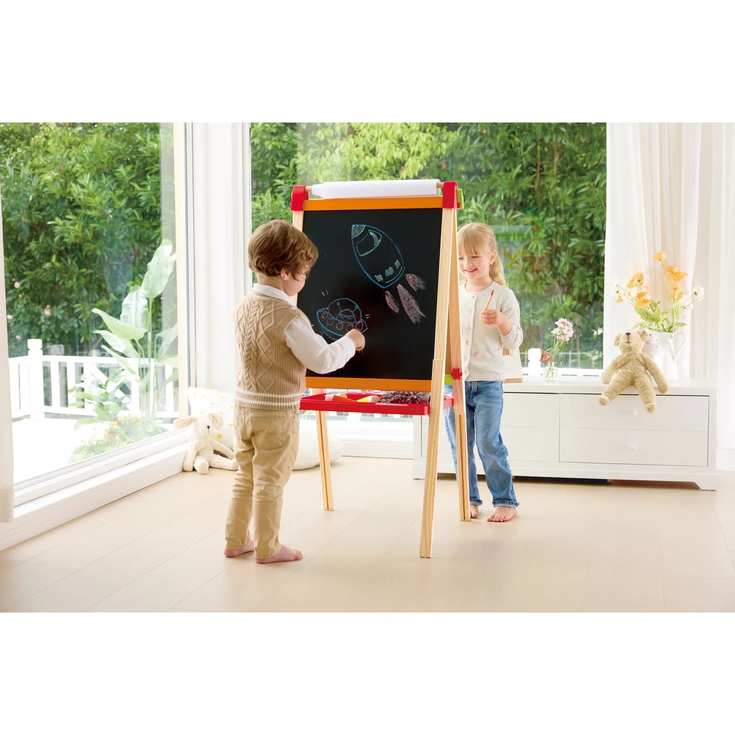 Two children playing with a colorful easel in a bright room with large windows.