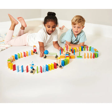 Two children playing with a colorful wooden domino set on a white surface.