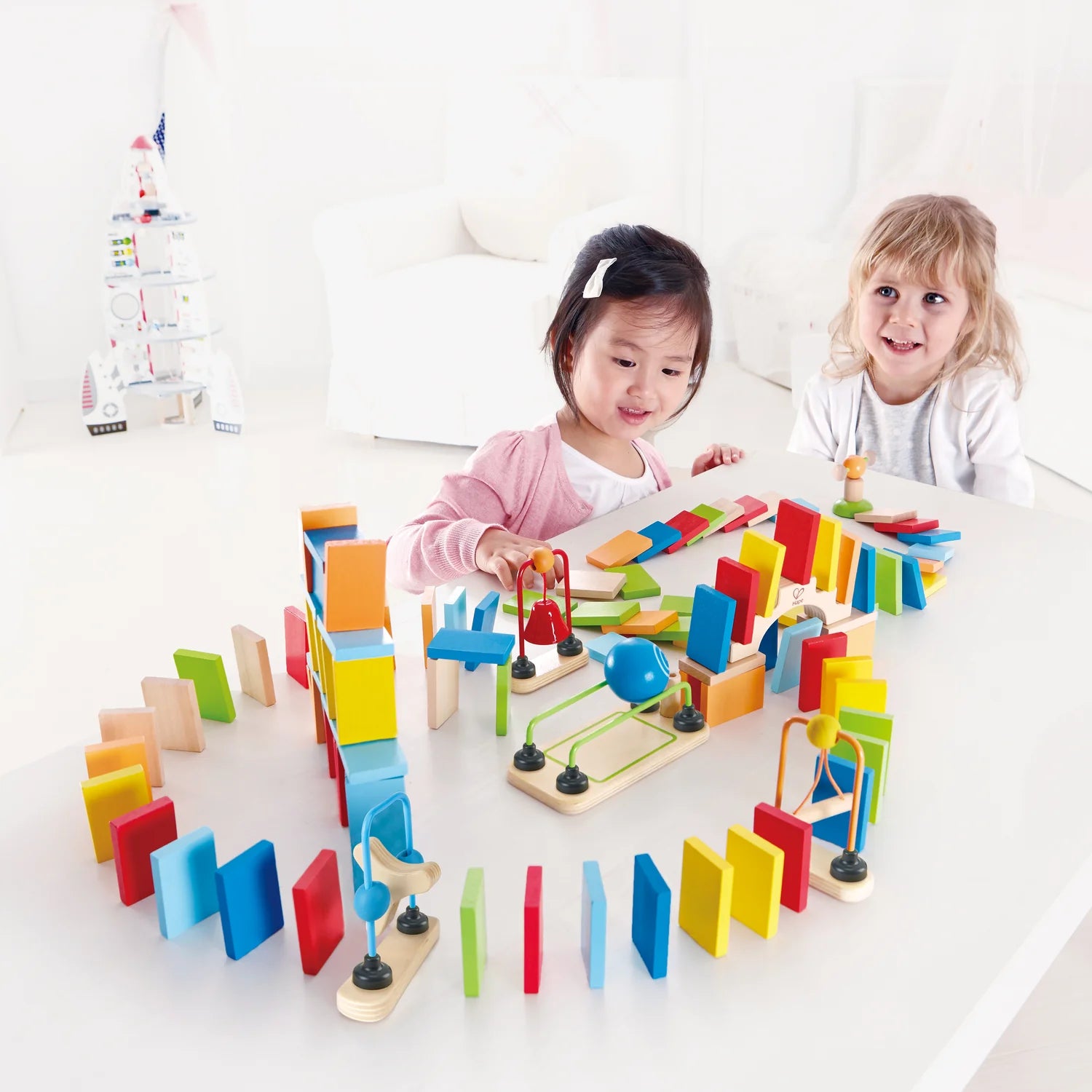 Two children playing with a colorful wooden toy set on a white surface.