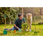Man and young girl gardening together in a backyard with gardening tools around them.