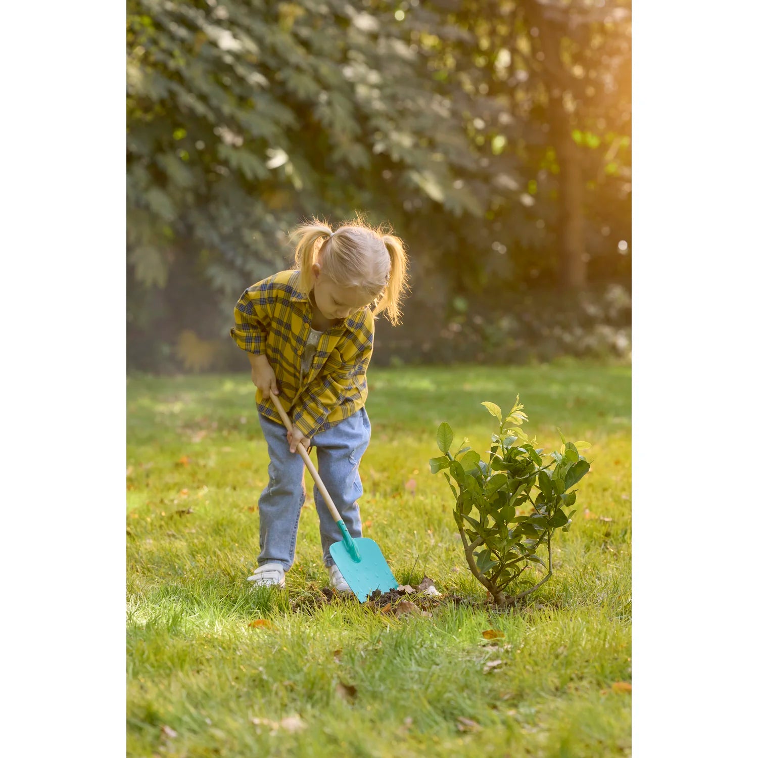Child gardening with a blue shovel in a grassy area