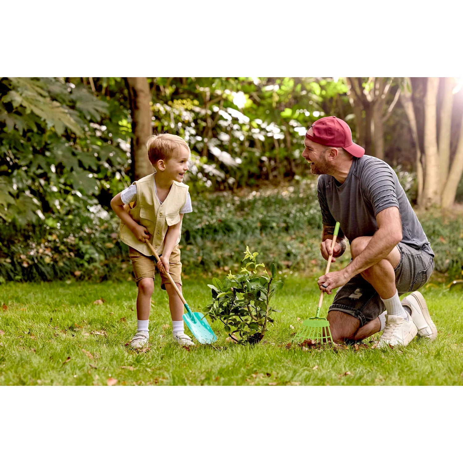 Man and child playing with gardening tools in a garden