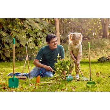 Man and child gardening together with tools on a grassy area