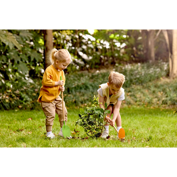 Two children planting a tree in a garden
