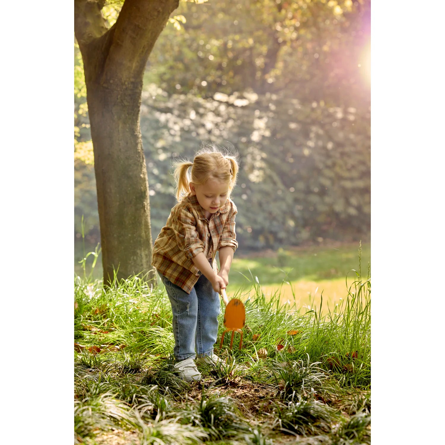 Child playing with a toy shovel in a grassy outdoor setting