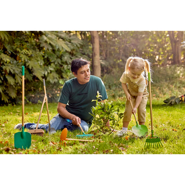 Man and child gardening together in a park with gardening tools around them.