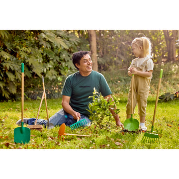 Man and child gardening together with tools on a grassy area