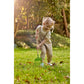 Child playing in a garden with a green tool, surrounded by trees and grass.