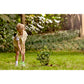 Child gardening in a lush green garden with trees and plants in the background