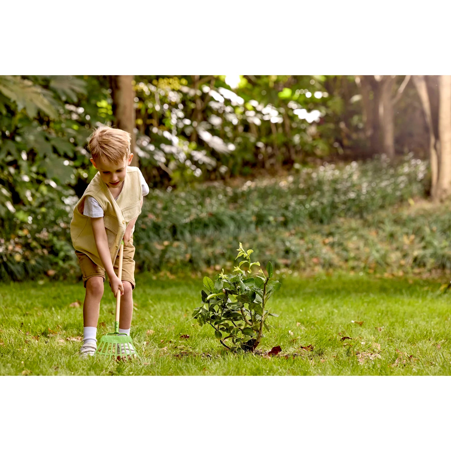 Child gardening in a lush green garden with trees and plants in the background