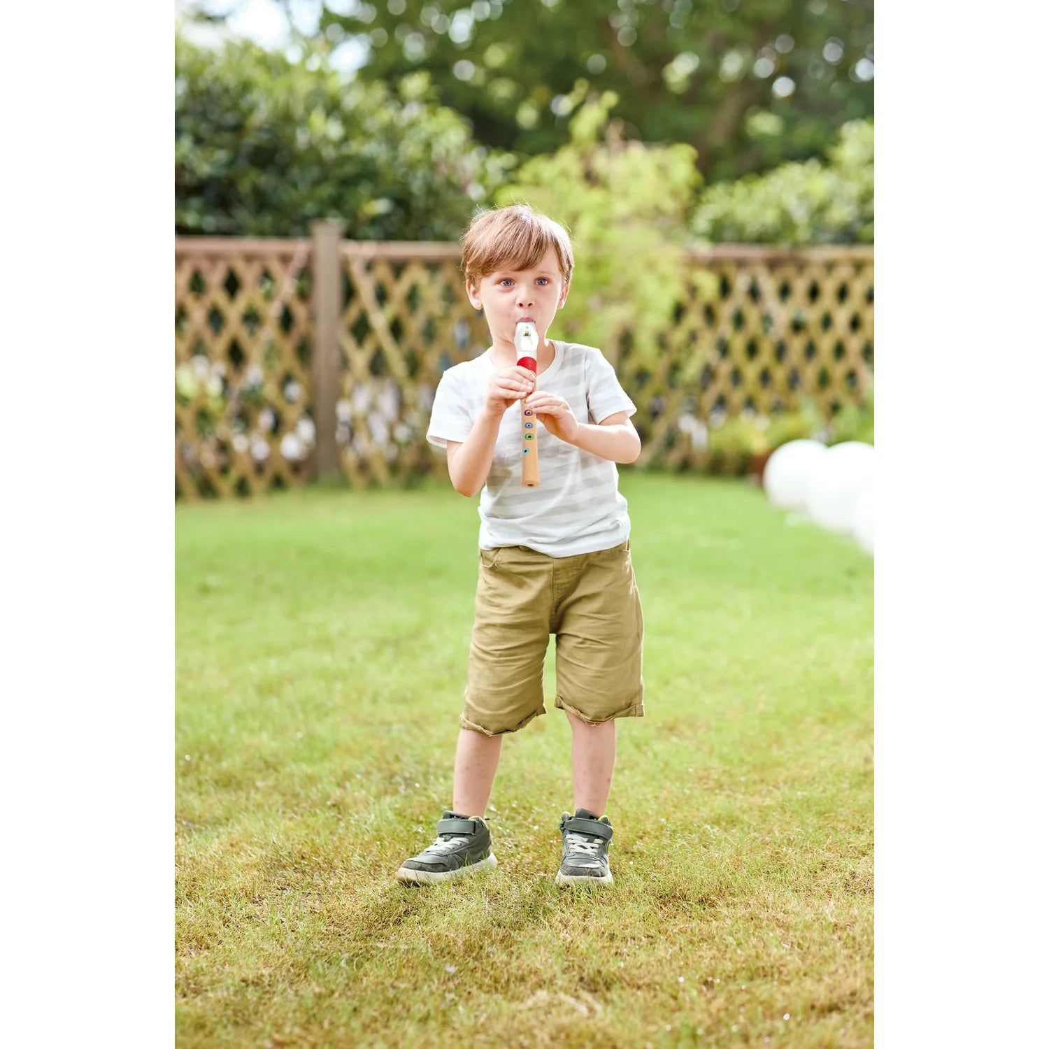 Child holding a recorder in a garden setting