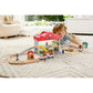 Child playing with a toy train set on a living room floor.
