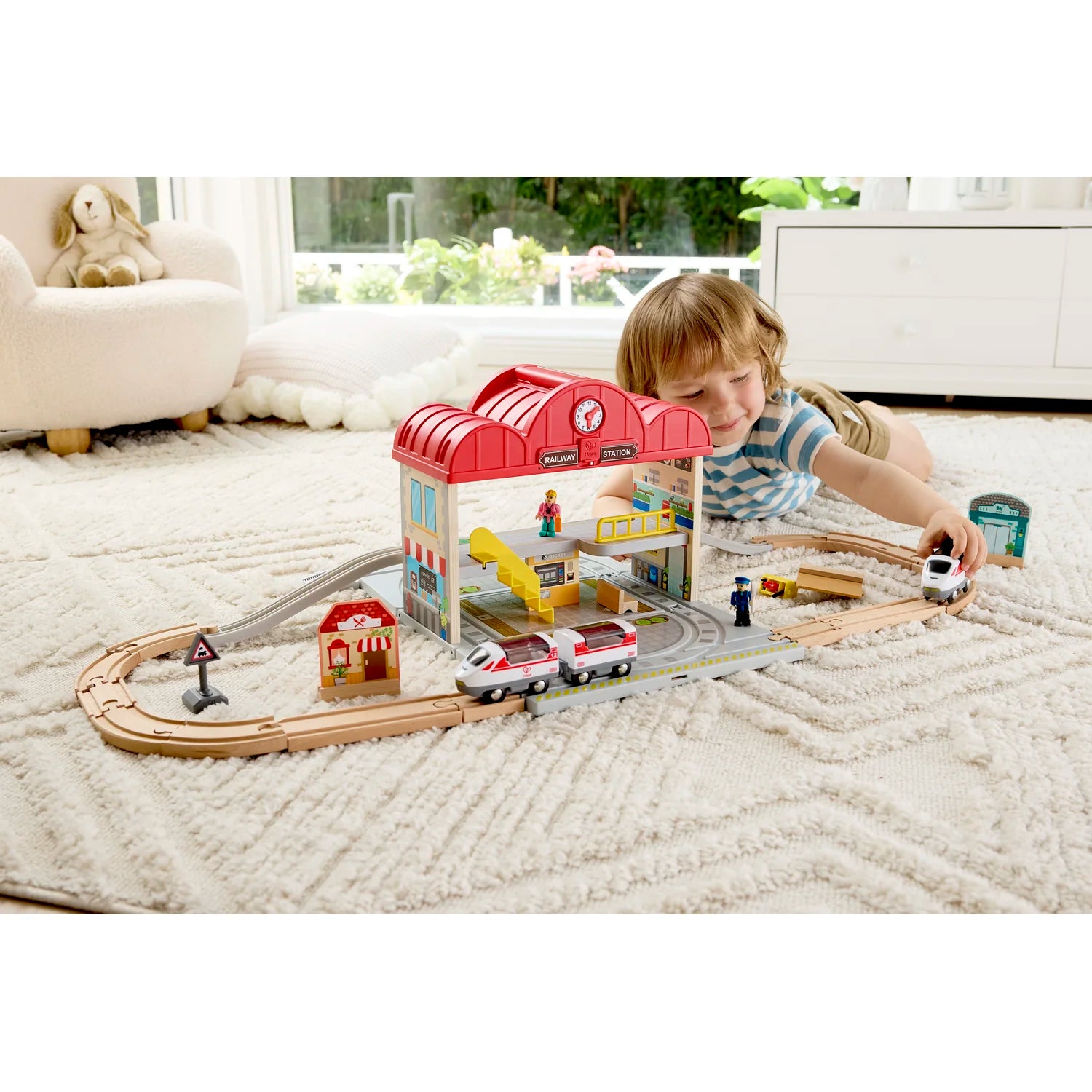 Child playing with a toy train set on a living room floor.