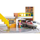 Toy train set with a station and a toy figure near a ticket machine.