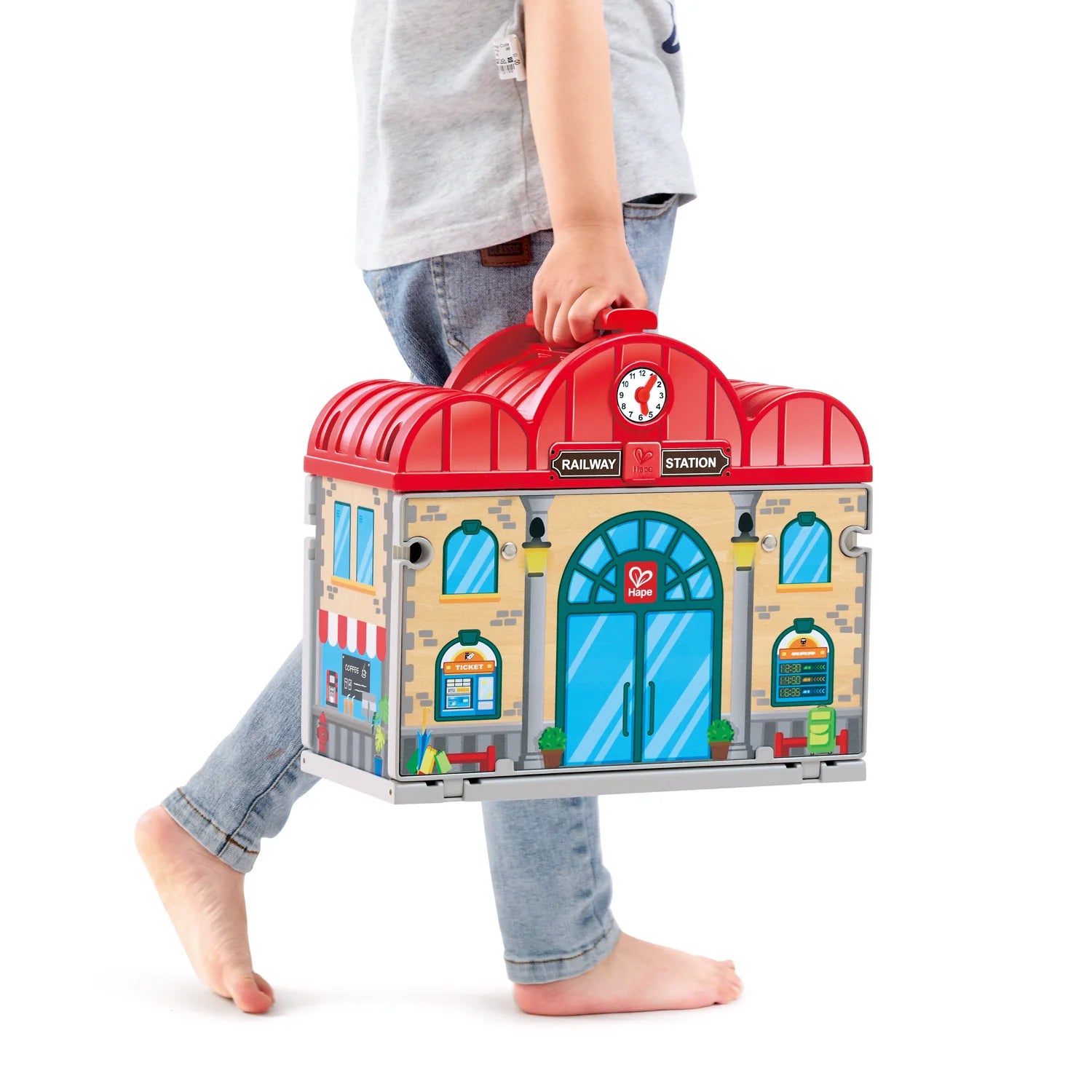 Child holding a toy train station set against a white background