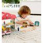 Child playing with a toy train set on a white carpet
