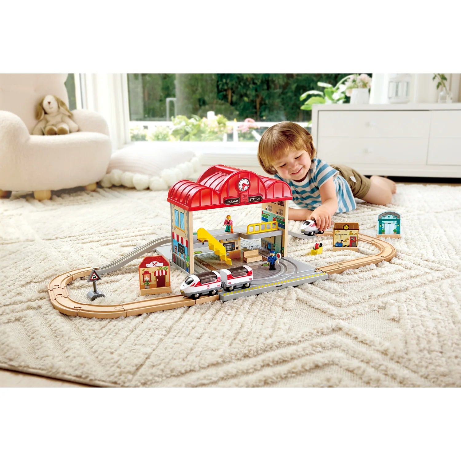 Child playing with a toy train set on a carpeted floor