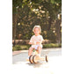 Child riding a tricycle in a park with trees in the background