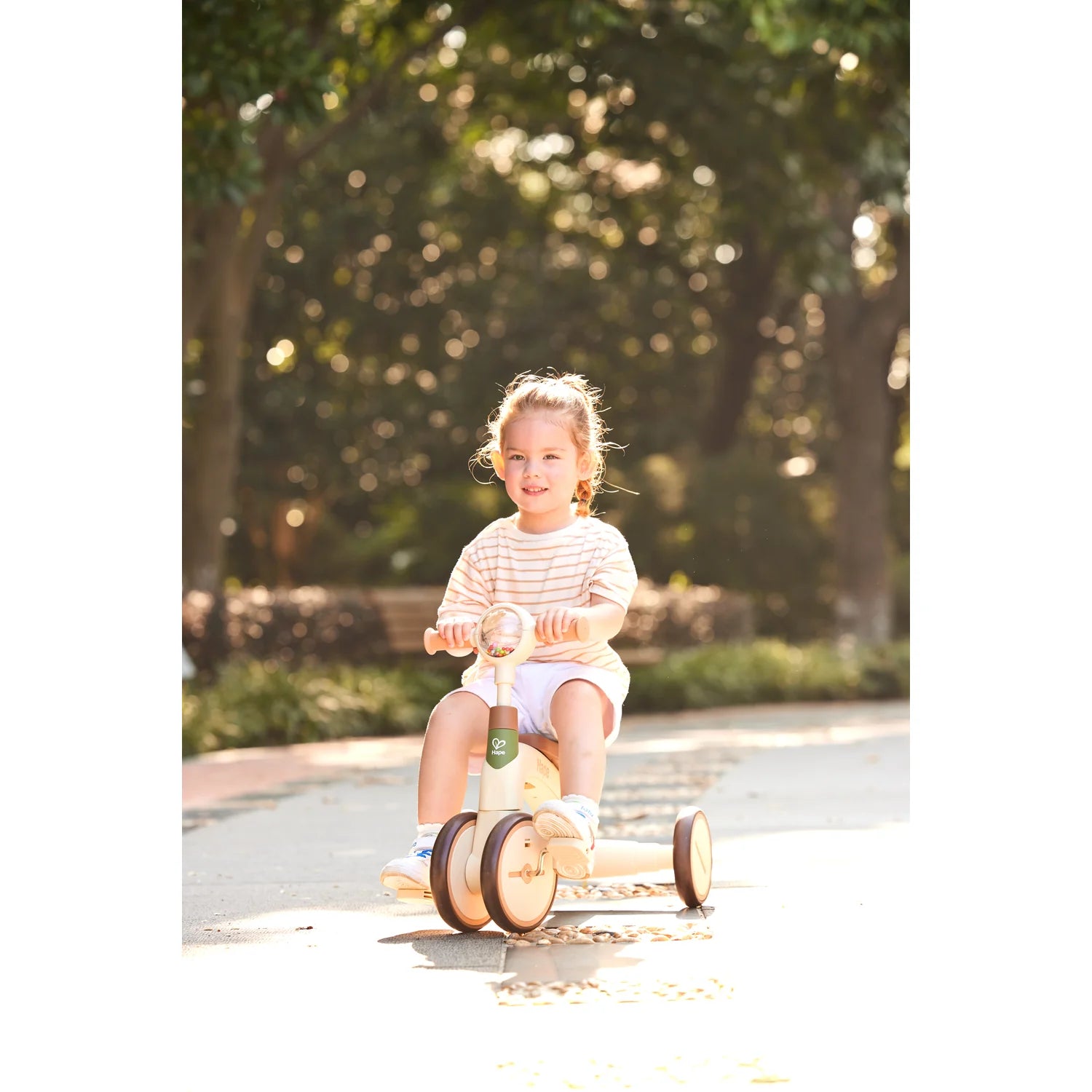 Child riding a tricycle in a park with trees in the background