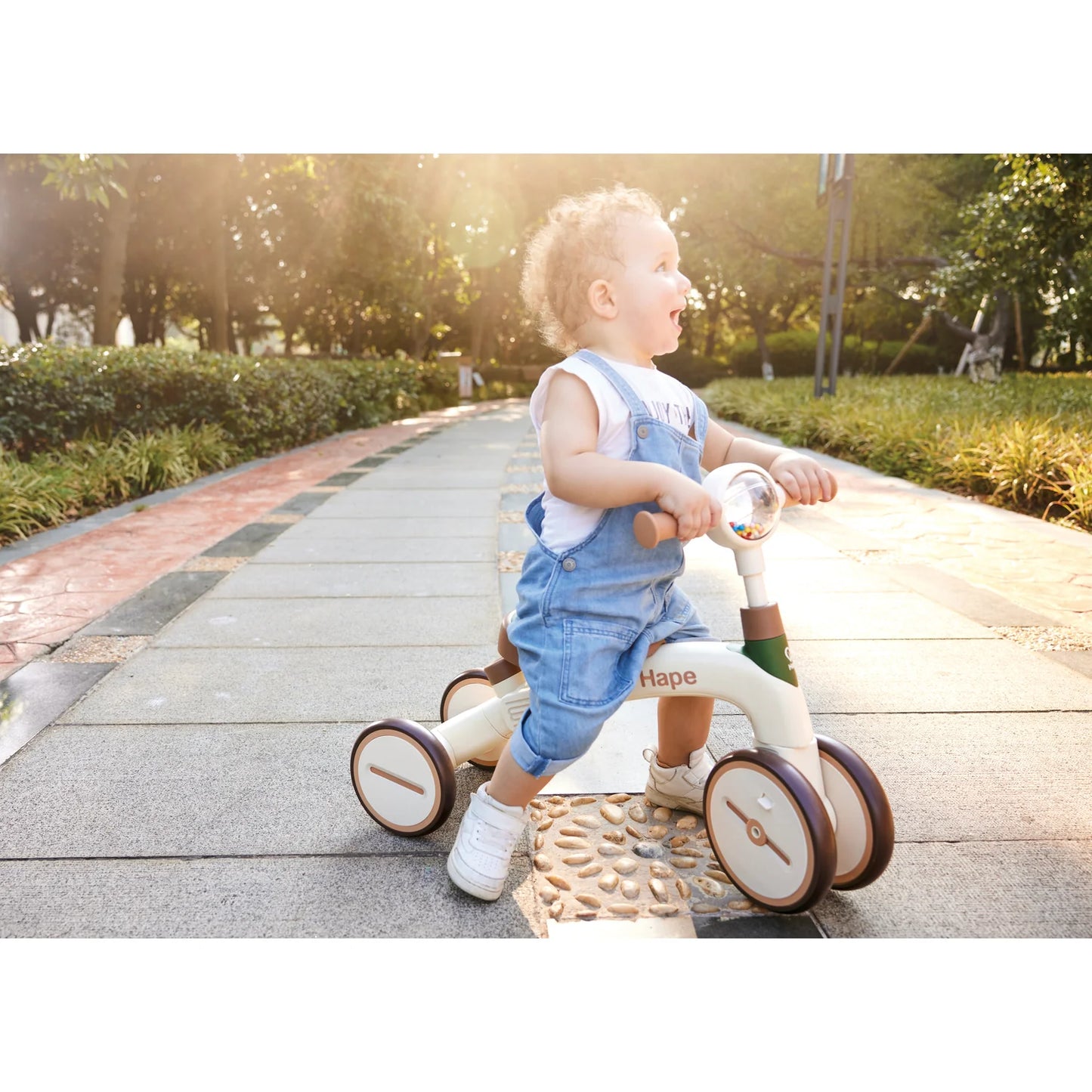 Child riding a Hape balance bike on a path in a park