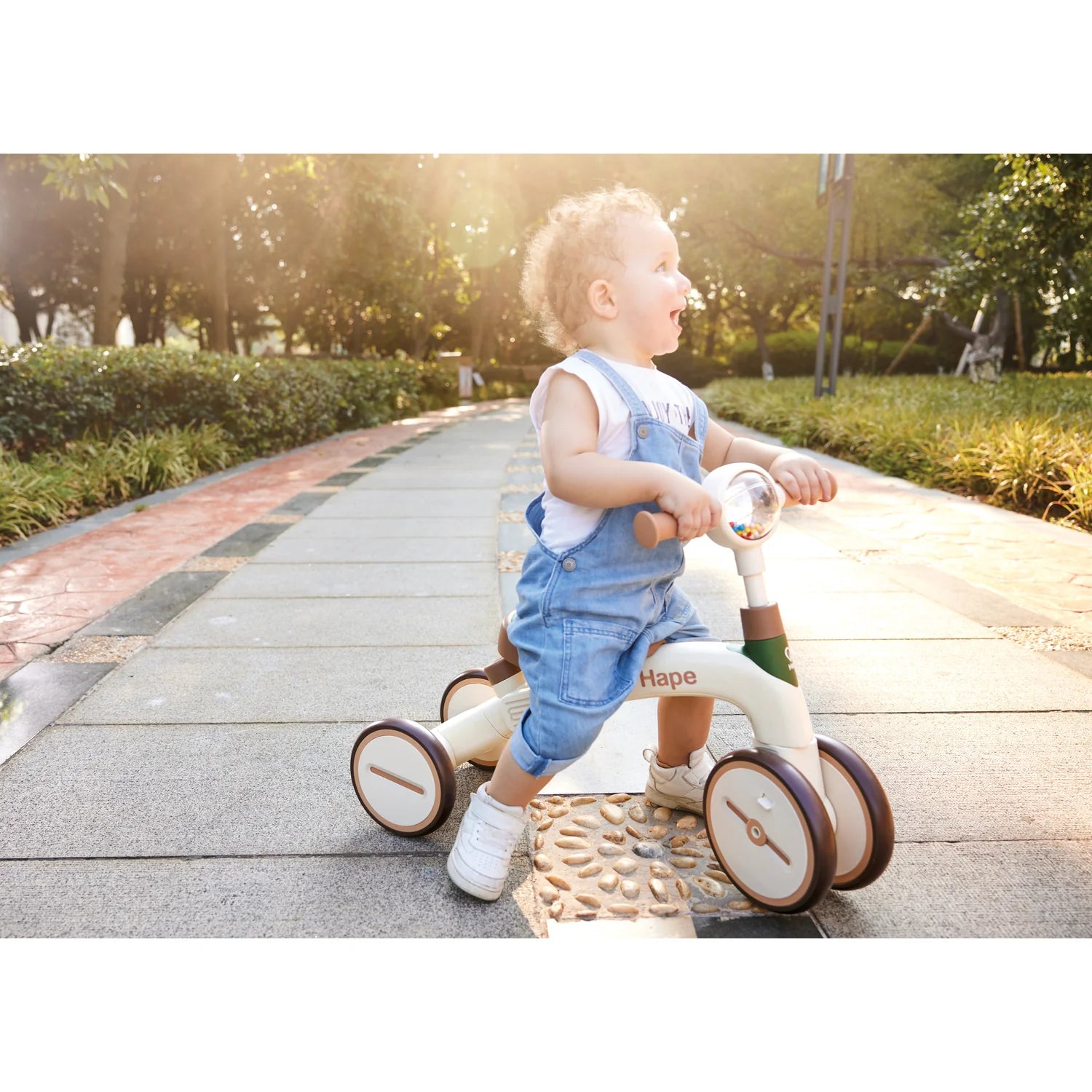 Child riding a Hape balance bike on a path in a park