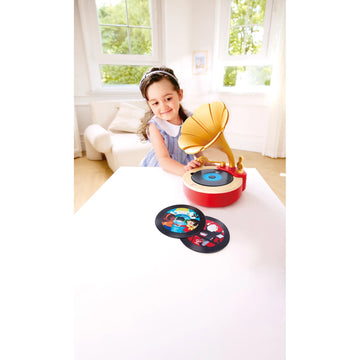 Child playing with a toy gramophone and records in a bright room.