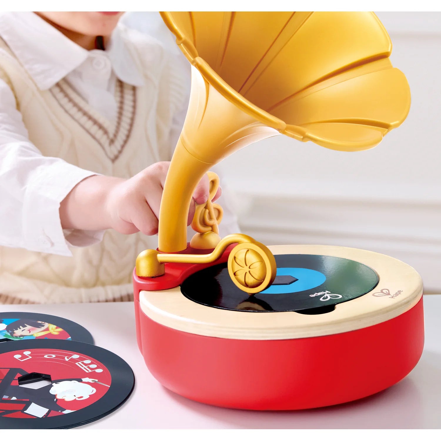 Toy record player with a child's hand interacting, on a light background