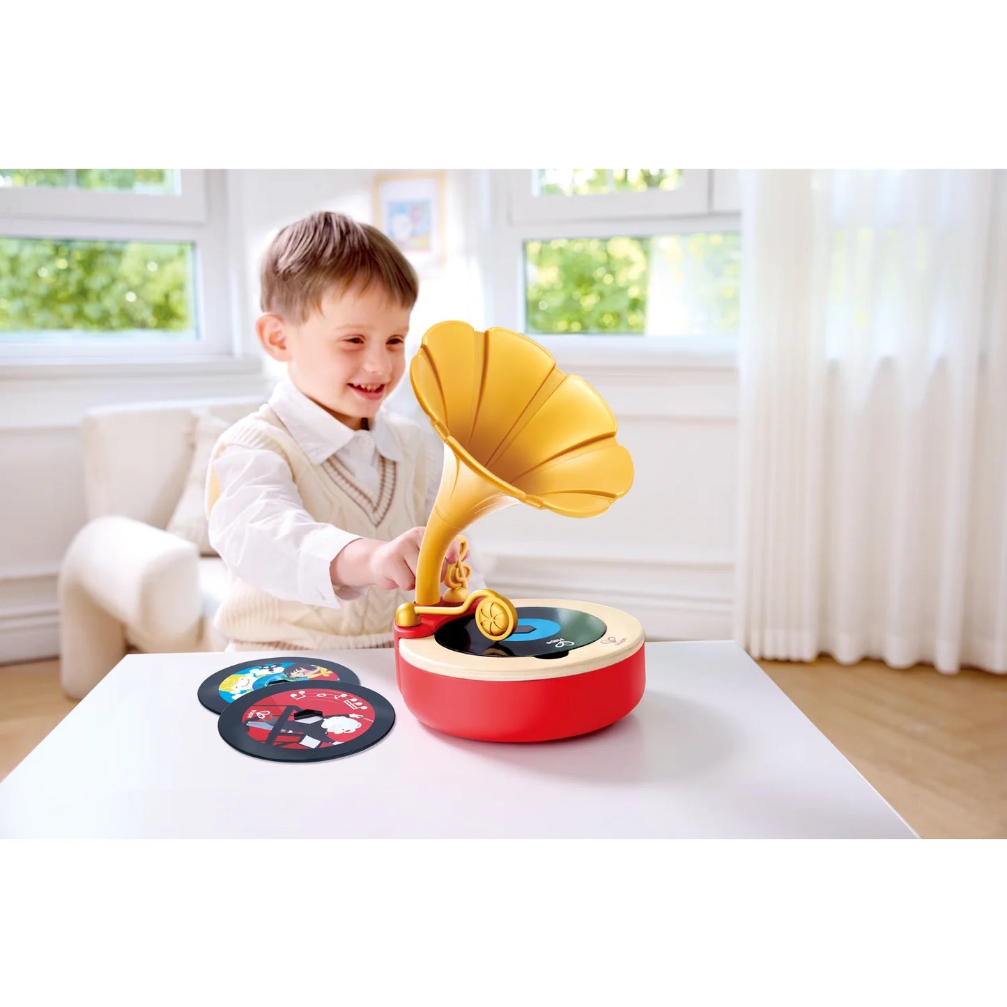 Child playing with a toy record player in a bright room.