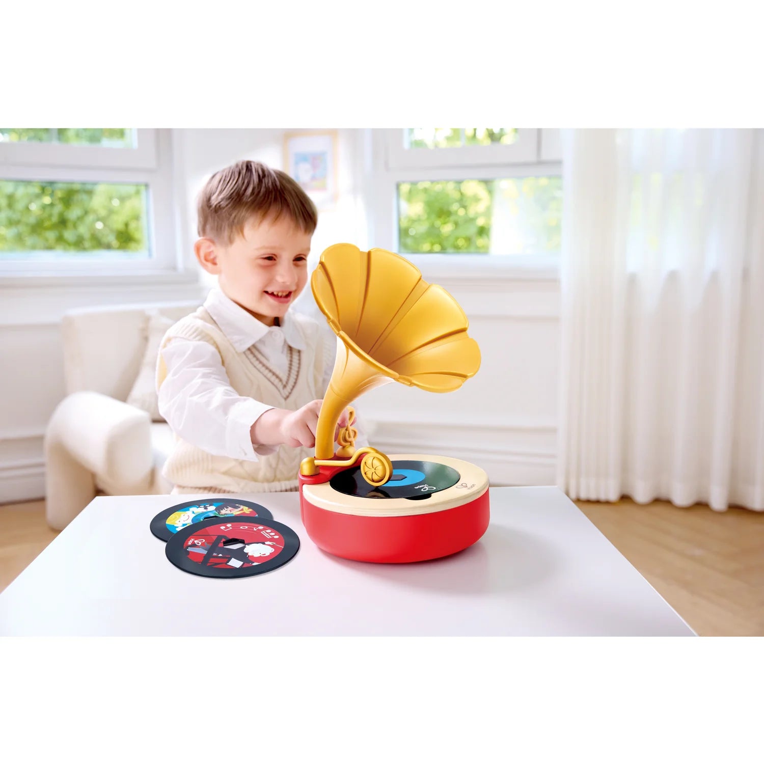 Child playing with a toy record player in a bright room.