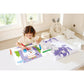 Child coloring on a table with coloring books and crayons in a bright room.