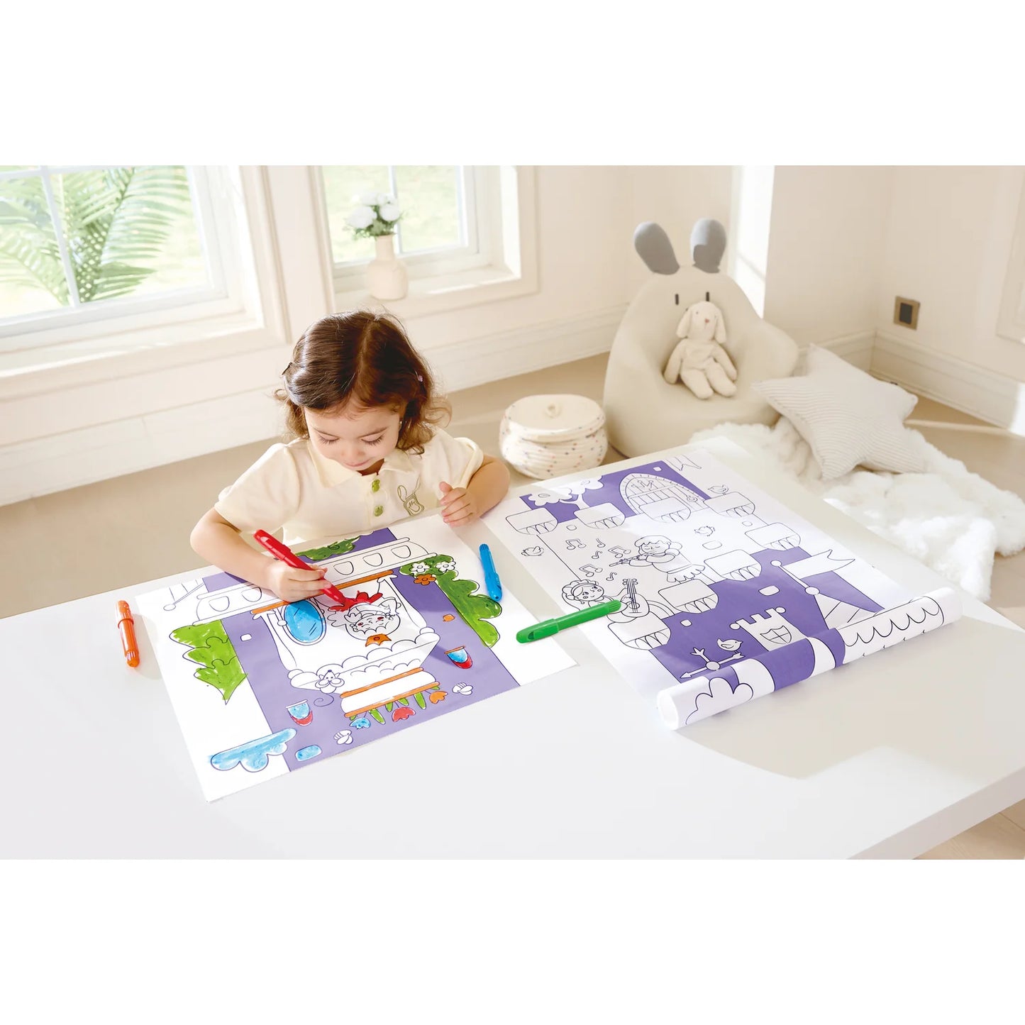 Child coloring on a table with coloring books and crayons in a bright room.