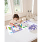 Child coloring on a table with coloring books and crayons in a bright room.