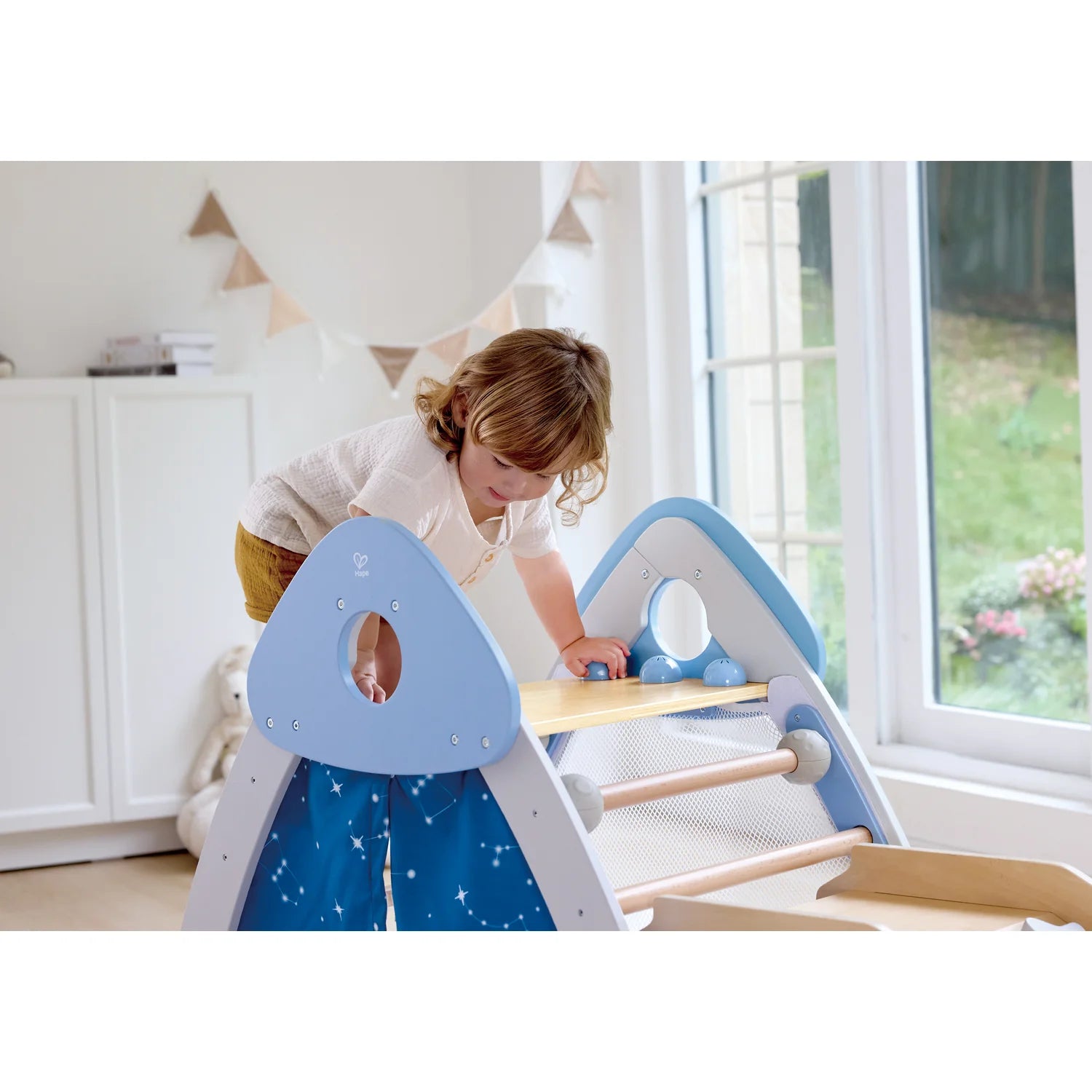 Child playing with a blue and white play structure indoors