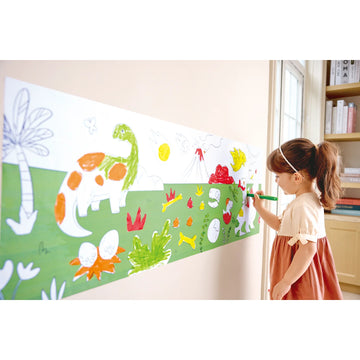 Child drawing on a large paper with dinosaur and plant illustrations in a room.