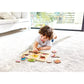 Child playing with a wooden puzzle on a carpeted floor in a living room.