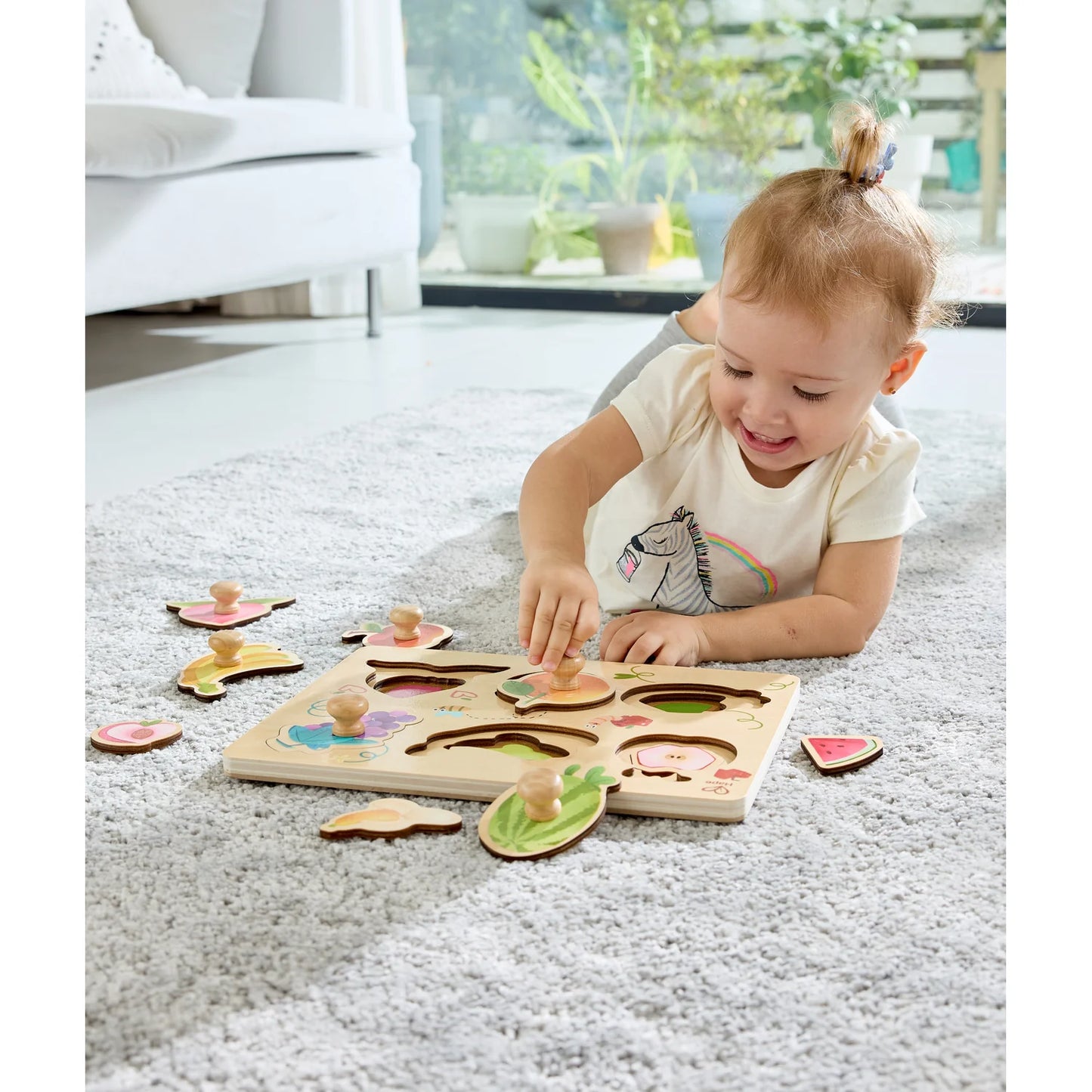 Child playing with a wooden puzzle on a carpeted floor.