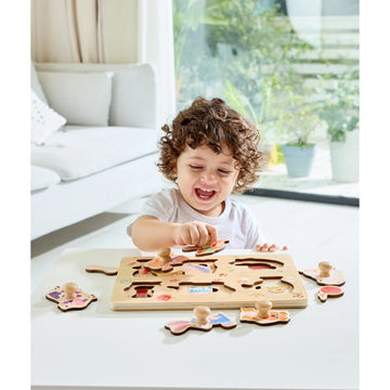 Child playing with a wooden puzzle toy in a bright room.