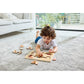 Child playing with a wooden puzzle on a carpeted floor in a living room.