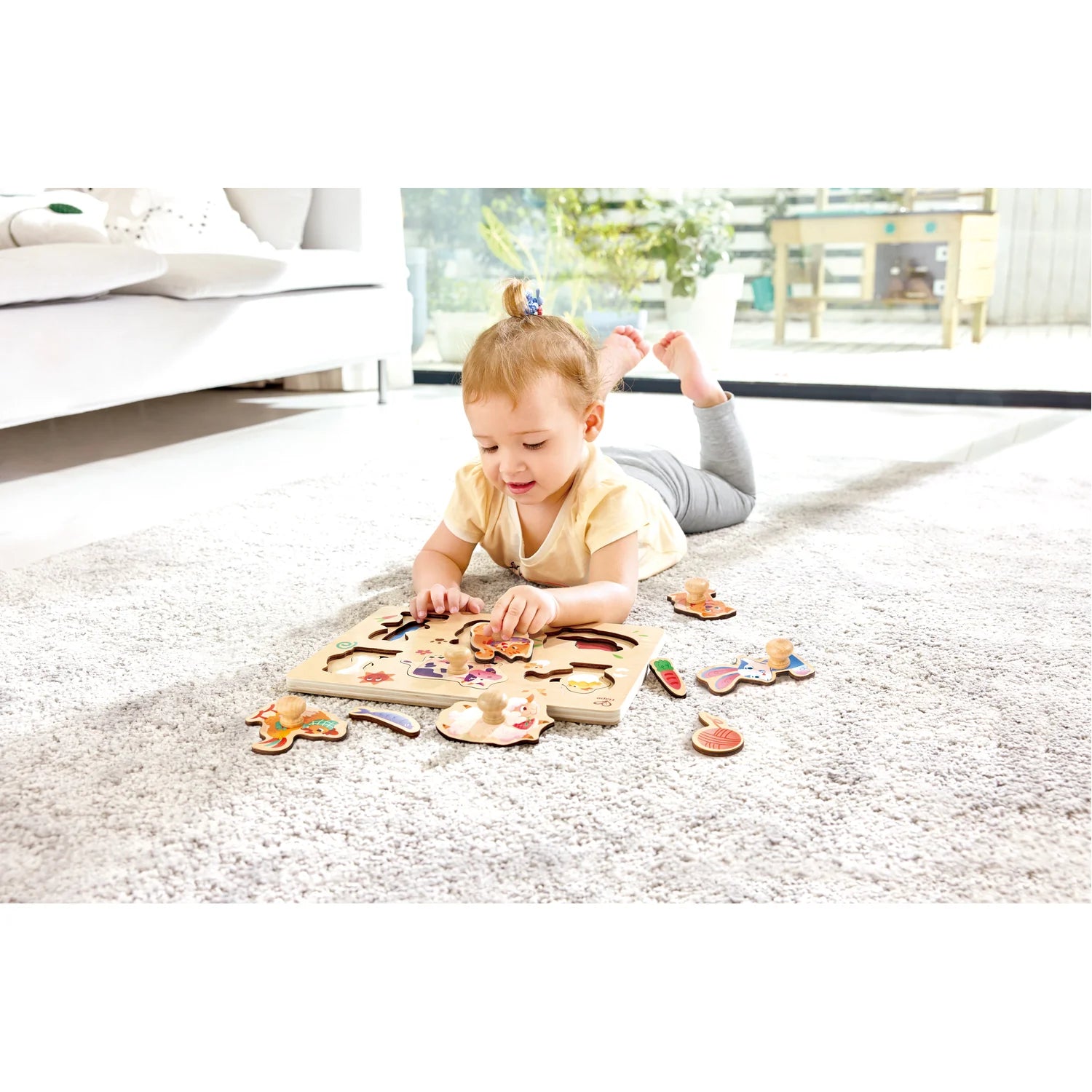 Child playing with a wooden puzzle on a carpeted floor.