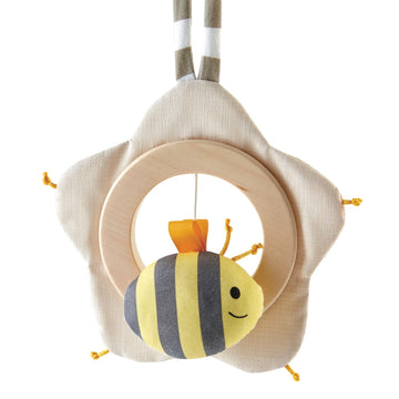 A beige and yellow flower-shaped music box with a smiling bee in the center that pulls away on a string, designed for babies.