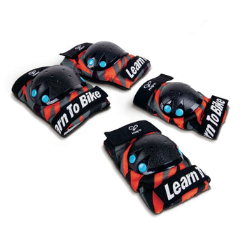 A set of black protective knee and elbow pads with orange stripes and text 'Learn To Ride'