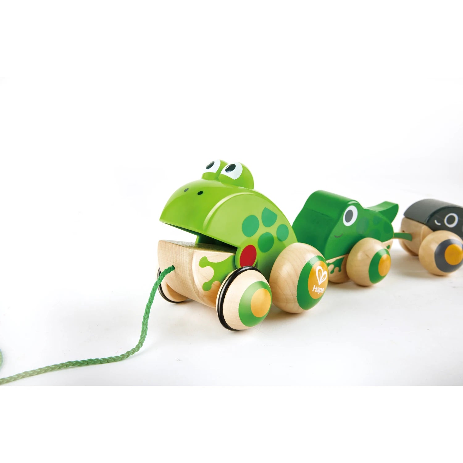 A wooden pull-along toy featuring a green frog with a froglet and a tadpole, connected by rubber-rimmed wheels that won't scratch the floor.