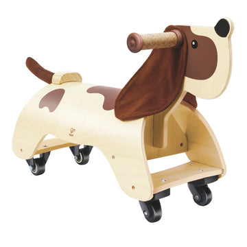 A wooden ride-on toy shaped like a dachshund with cork handles and corduroy ears, designed for toddlers.