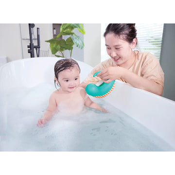 Woman and child in a bathtub with a green toy, surrounded by bubbles.