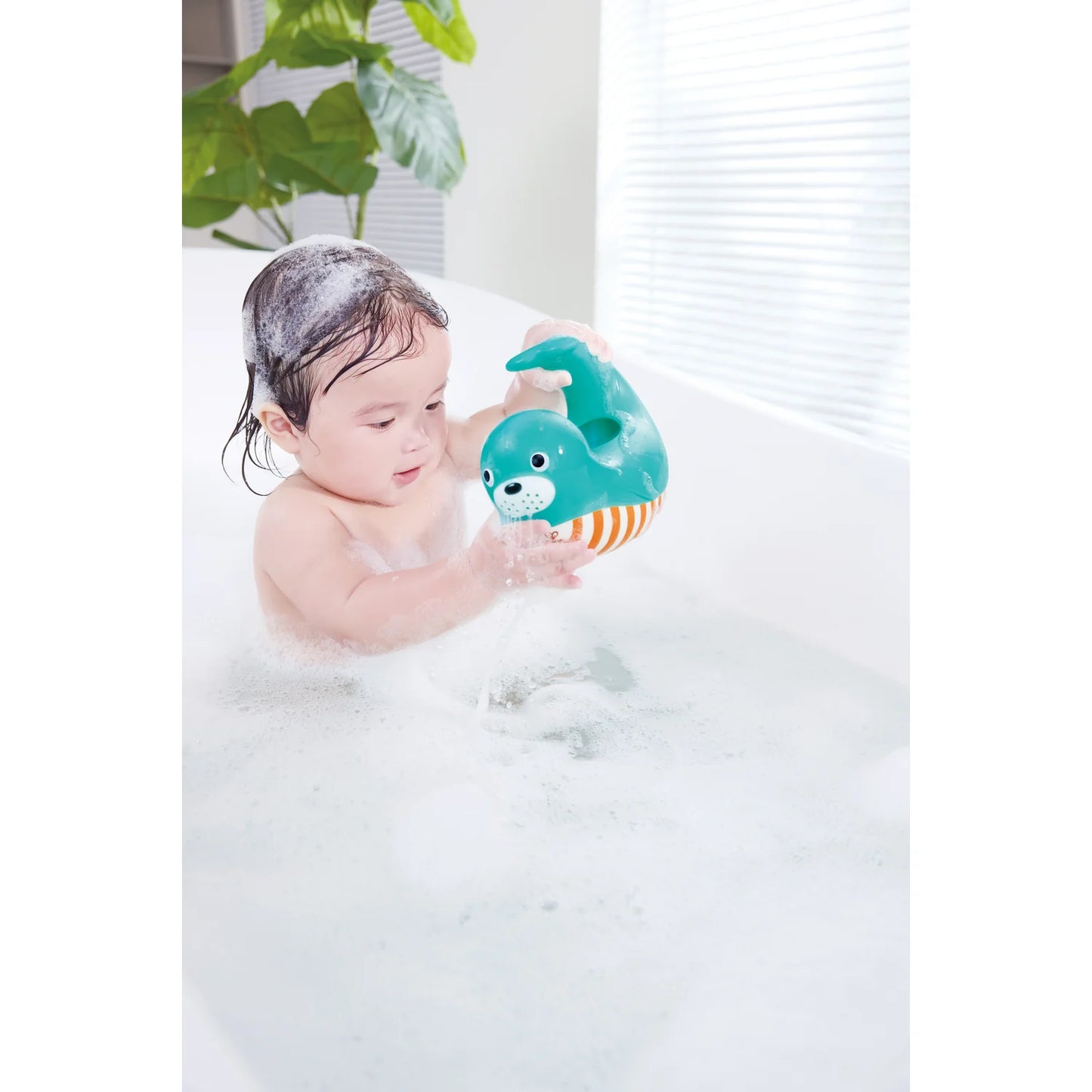 Child playing with a green toy in a bubble bath