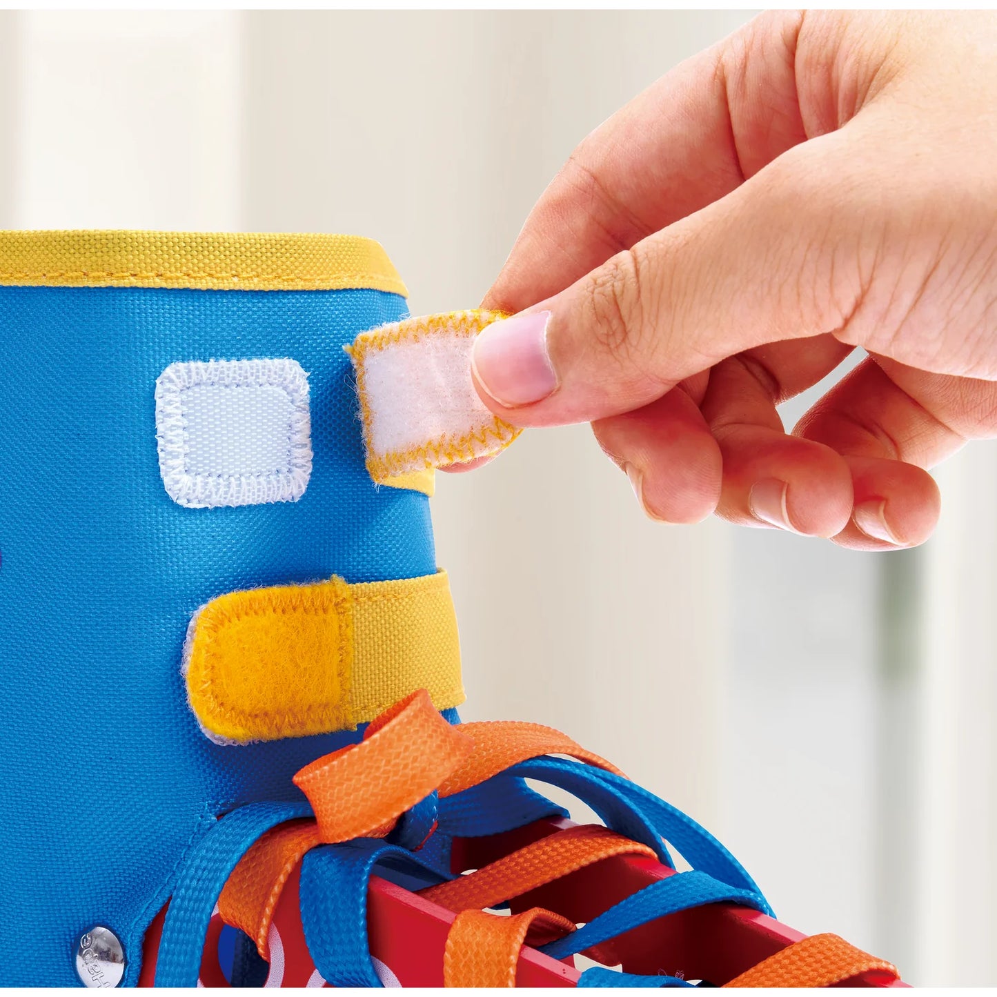 Colorful toy with a hand adjusting a strap on a light background
