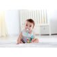 Baby sitting on a bed with a colorful teething ring