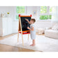 Child drawing on a blackboard easel in a bright living room.