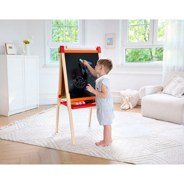 Child drawing on a blackboard easel in a bright living room.